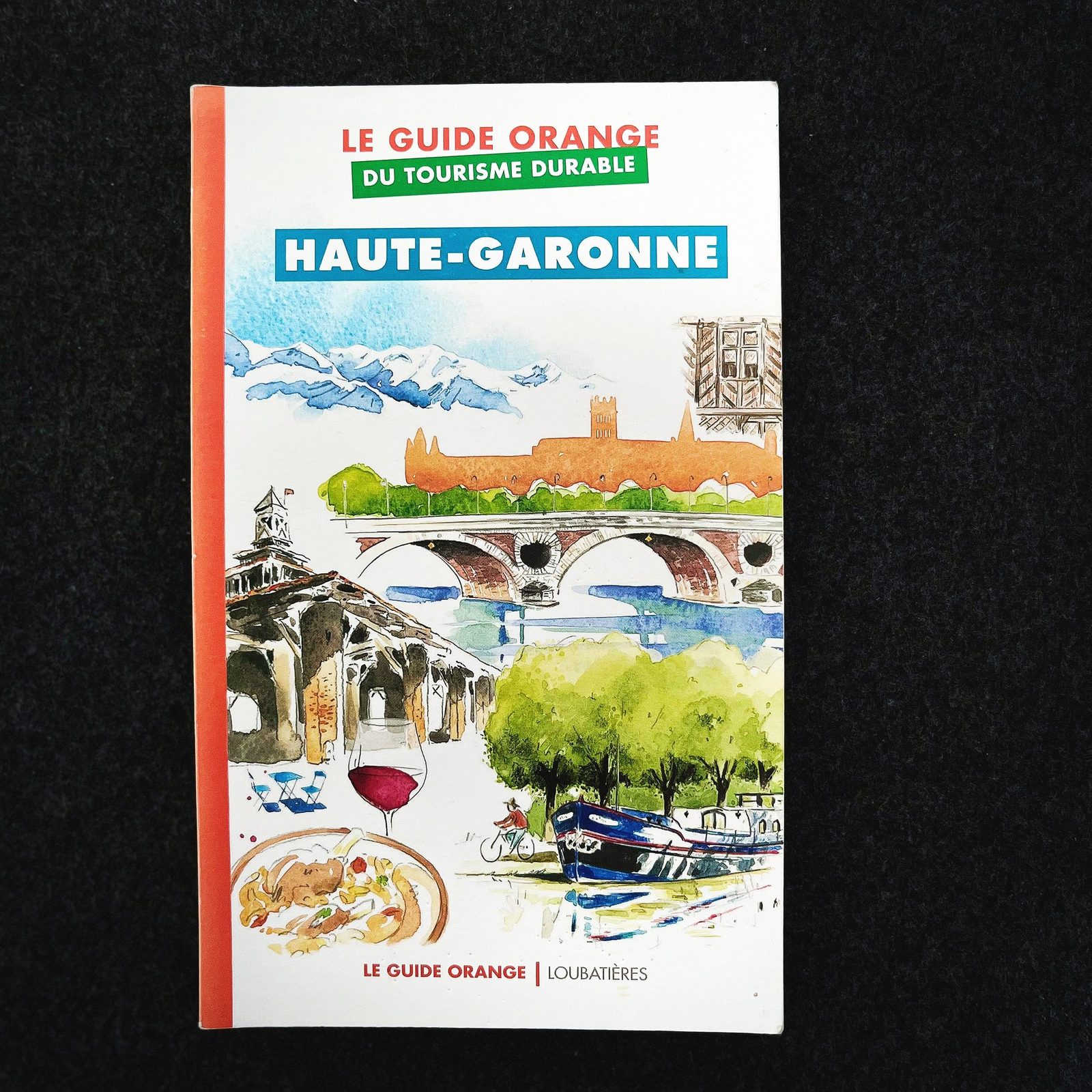 Couverture du guide orange sur le tourisme durable à Haute-Garonne, illustrée d'une peinture représentant un pont, un canal, des arbres, une montagne et un verre de vin rouge